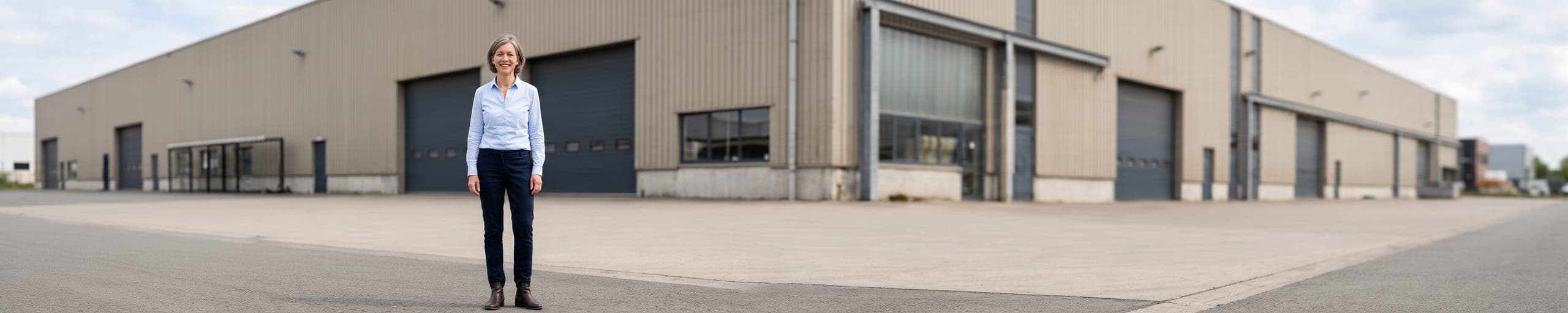 Propriétaire de bâtiment industriel examinant la façade et la toiture d'un entrepôt, dossier de documents à la main